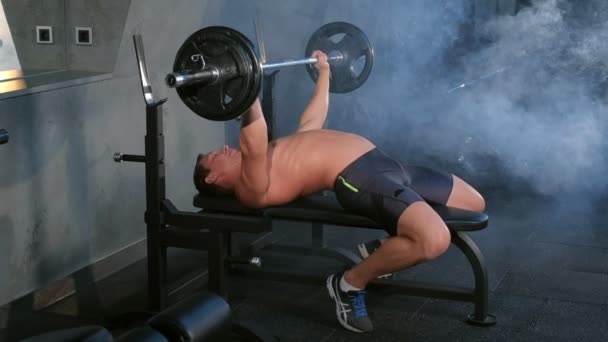 Professionele gespierde atletische man bodybuilder doet lange halter oefening op bank. — Stockvideo