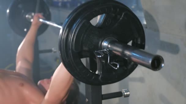 운동 선수 보디빌더가 벤치에서 바 종 가슴 운동을 하는 모습, 클로즈업 뷰. — 비디오