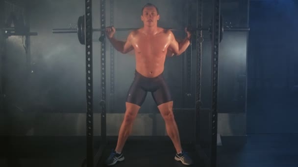 Man bodybuilder gör squat motion med skivstång på smed maskin på gym. — Stockvideo