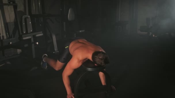 Fatigué jeune homme bodybuilder couché sur le banc de repos dans la salle de gym après l'entraînement . — Video