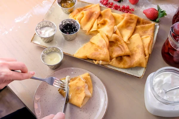 Nő az evés orosz hagyományos palacsinta, blini tálalva lekvárok, tejföl, eper és a tányéron. Közeli felülnézet. — Stock Fotó