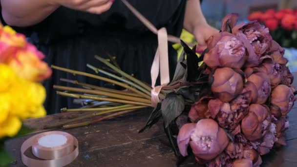 花屋の茶色のピオニーの花束にリボンでつながった女性花屋のネクタイ. — ストック動画