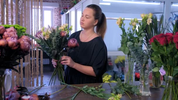 Флорист создает букет эвкалипта, эустомы, пиона и радужки в цветочном магазине . — стоковое видео