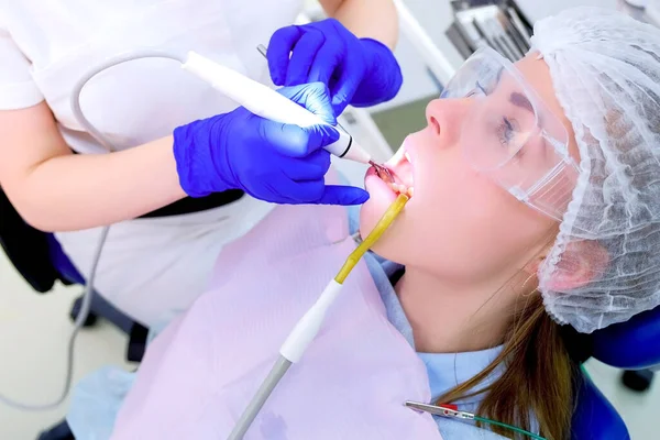 Patient woman on ultrasonic teeth cleaning procedure in dentistry, side view. — Stock Photo, Image