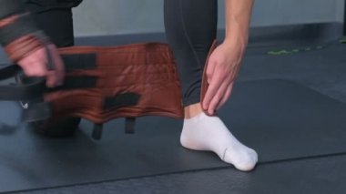 Sporcu, spor salonunda miyofasyal esneme için bacağa deri sabitleyici takıyor..