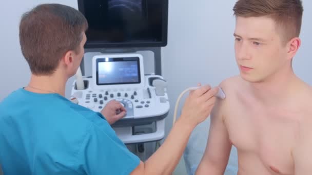 Le médecin fait une échographie de l'articulation de l'épaule pour l'homme en utilisant un scanner à ultrasons . — Video