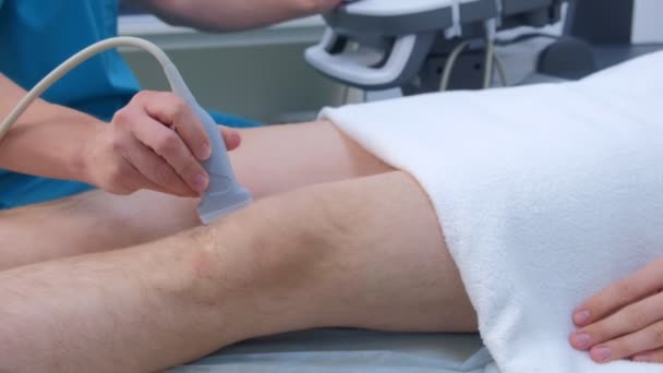 El médico hace ultrasonido de la articulación de la rodilla para el hombre utilizando el escáner de ultrasonido, primer plano . — Vídeo de stock