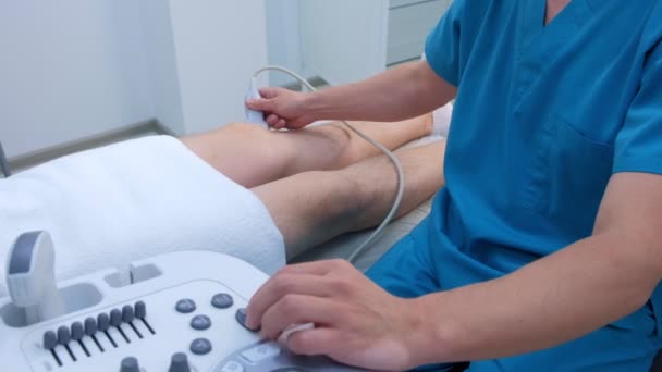 Arzt macht Ultraschall des Kniegelenks bei Mann mit Ultraschallscanner. — Stockvideo