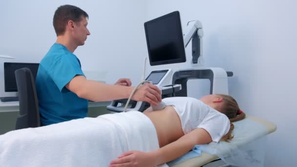 Чоловік лікар робить черевний ультразвук для діагностики шлунку жінці в клініці . — стокове відео