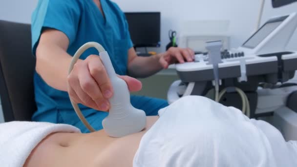 Hombre médico haciendo ultrasonido abdominal para diagnosticar estómago a mujer en la clínica . — Vídeo de stock