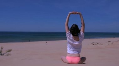 Kadın streç yoga uygulama lotus poz kumlu deniz plaj eller yukarı görünümü oturur.
