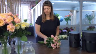 Çiçekçide çiçek buketi yapan kadın..