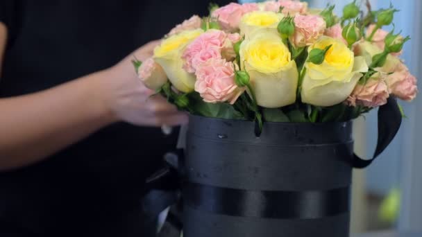 Ανθοπωλείο γυναίκα κάνοντας μπουκέτο τριαντάφυλλα σε συσκευασία μαύρο κουτί στο κατάστημα, closeup. — Αρχείο Βίντεο