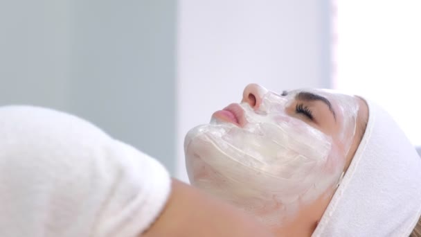 Portrait de femme allongé dans un salon de spa avec masque blanc sur le visage, vue latérale . — Video