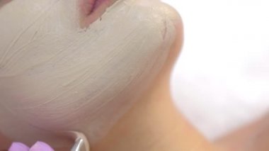 Güzellik kliniğinde kadın hasta yüzüne cilt bakımı için maske takıyor..