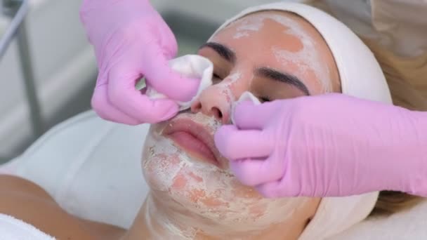 Cosmetologist em luvas esfregando a máscara da cara de mulheres, close-up retrato . — Vídeo de Stock