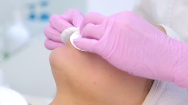 Косметолог в перчатках очищает клиентов женское лицо салфетками . — стоковое видео