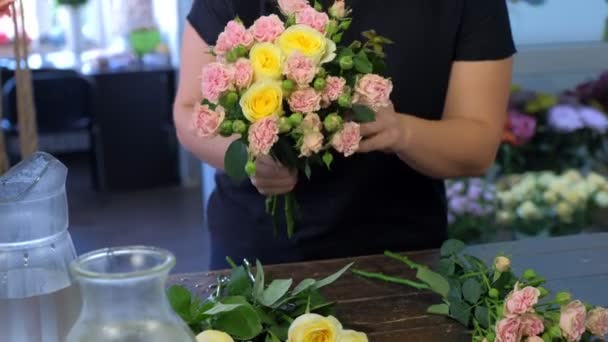 Blumenhändlerin macht Blumenstrauß aus verschiedenen Sorten Rosen, Hände Nahaufnahme. — Stockvideo