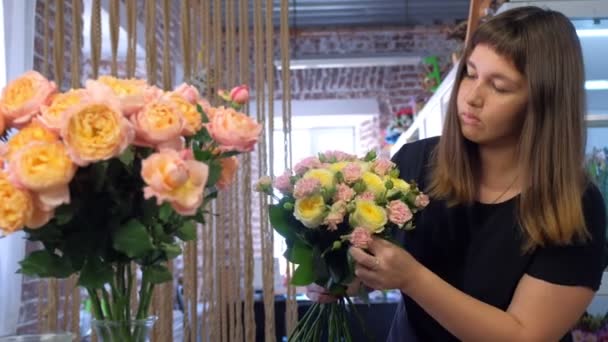 Mulher florista fazendo flores buquê de diferentes tipos de rosas na loja de flores . — Vídeo de Stock