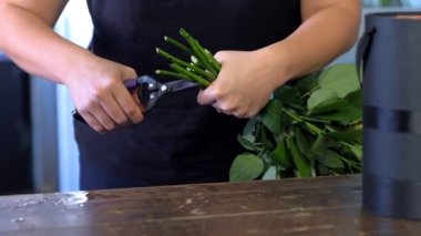 Çiçekçi kadın çiçek hazırlar dükkanda gül sapları, yakın çekim elleri.