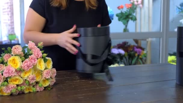 Florista faz cria buquê com rosas preparando caixa de embalagem, mãos close-up . — Vídeo de Stock