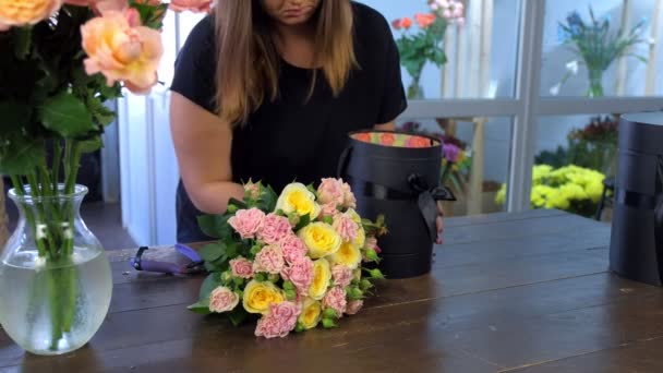 Florista mulher fazendo buquê de rosas colocando-o em caixa de embalagem na loja . — Vídeo de Stock