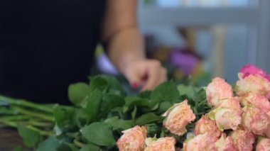 Çiçekçi kadın çiçekçide pembe şakayık buketi yapıyor, yakın çekim manzaralı..