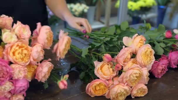 Květinářská žena dělat kytice růžové a oranžové pivoňky v květinářství, detailní up. — Stock video
