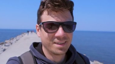 Portre adam görüntülü sohbetler selfie smartphone deniz plajı iskele yürüyüşleri ve gülümsüyor.