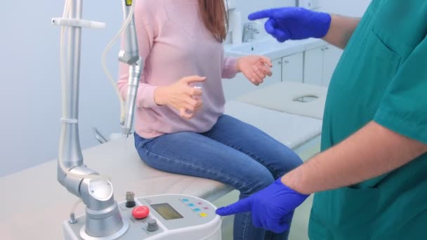 Cirujano explica a la mujer procedimiento paciente de eliminación de láser verruga en el dedo . — Vídeo de stock
