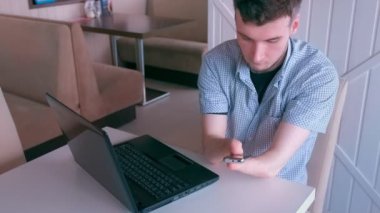 Kesik elleri olan engelli bir adam kafede cep telefonuna mesaj yazıyor..