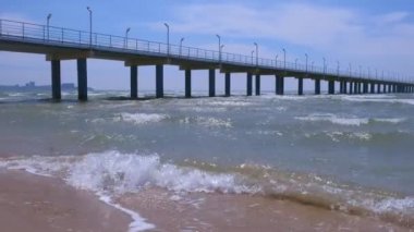 Güneşli bir günde dalgalar iskele sahil kenti ve dağlar ile deniz kum plaj manzarası.