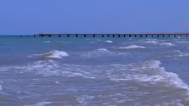 Naturlandschaft mit langen Wellen, Himmel und Seebrücke bei sonnigem Tag. — Stockvideo