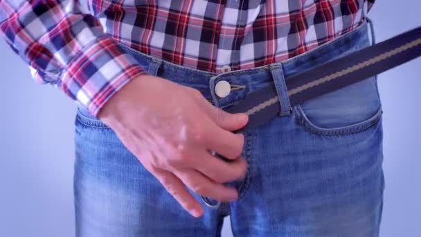 El hombre se está poniendo el cinturón en sus jeans, cintura y manos de cerca . — Vídeo de stock