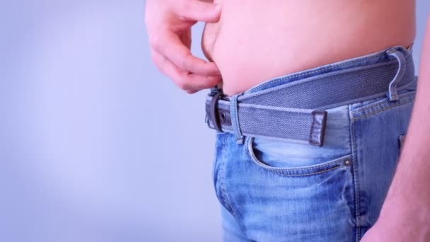 Joven pellizca el exceso de grasa que tiene alrededor de su cintura, vista lateral . — Vídeos de Stock