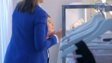 Makeup artist allying lipstick with brush on girl model lips before mirror.