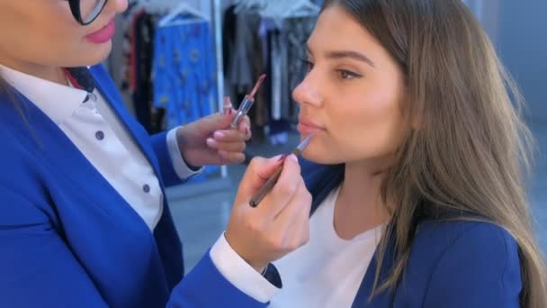 Make-up umělec aplikuje lesk na rty používá štětec na dívky modelka rty v salonu krásy. — Stock video