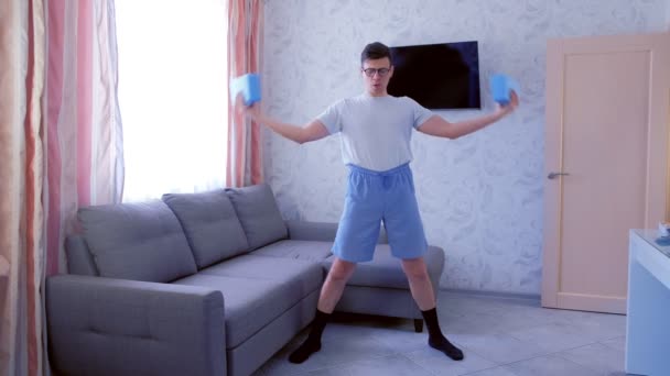 Homem nerd engraçado está fazendo exercícios de fitness para mãos com blocos de ioga em vez de halteres em casa. Conceito de humor esportivo . — Vídeo de Stock