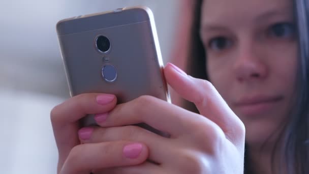 Νεαρή γυναίκα κοιτάζει μέσα και διαβάζει μηνύματα στο smartphone κρατά στα χέρια. — Αρχείο Βίντεο