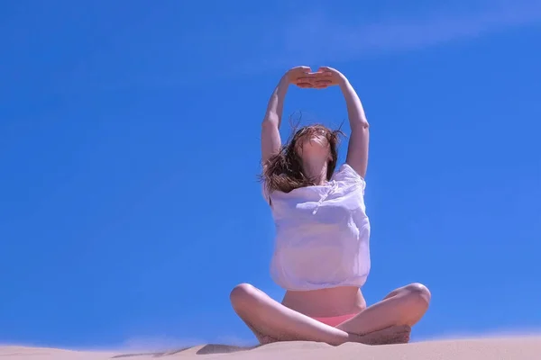 Mujer estiramiento se sienta loto pose playa de arena vacaciones de verano manos hasta día ventoso . —  Fotos de Stock