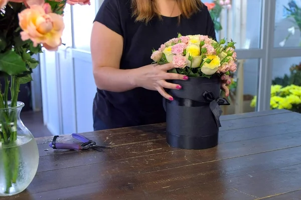 Florista mulher fazendo buquê de rosas colocando-o em caixa de embalagem na loja . — Fotografia de Stock