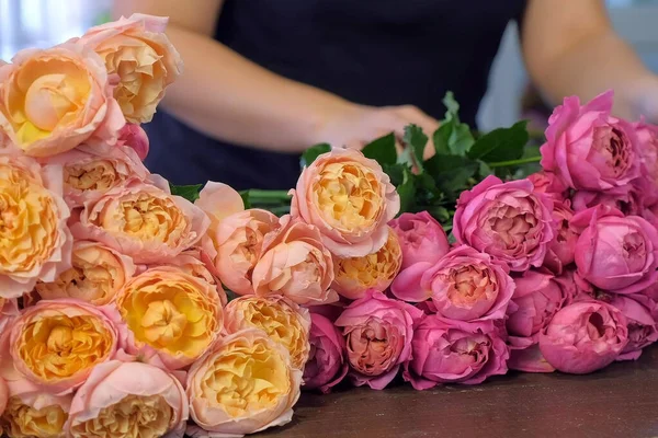 Kwiaciarnia kobieta przygotowuje różowe i pomarańczowe piwonie do bukietu w kwiaciarni. — Zdjęcie stockowe