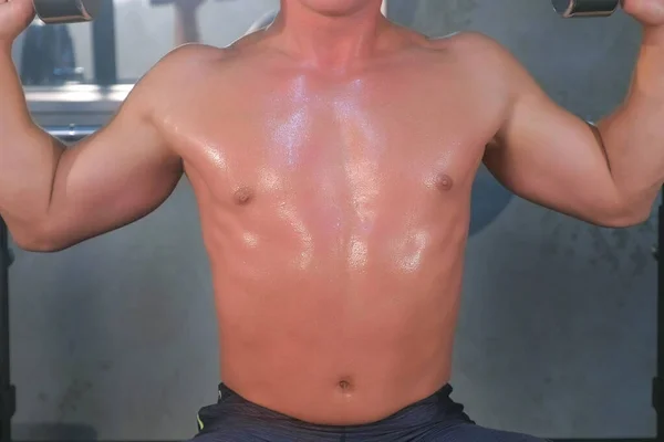 Musculoso joven haciendo hombros sobre la cabeza levantamiento de prensa con pesas en el gimnasio . —  Fotos de Stock