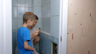 Baba ve oğul evde birlikte tamirat yapıyor, tuvaletteki duvarları söküyorlar..