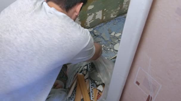 Мужчина убирает строительный мусор после ремонта и ремонта дома . — стоковое видео