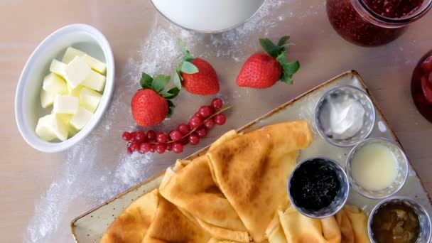 Traditionele Russische pannenkoeken, blini. Geserveerd met jam, zure room, melk en aardbeien op de plaat. — Stockvideo