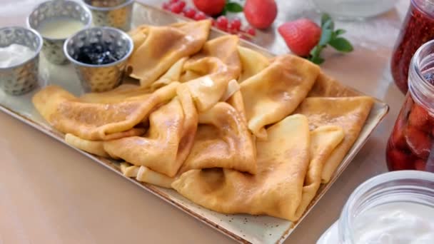 俄罗斯传统的煎饼, 在盘子里放了果酱、酸奶油和草莓。特写视图. — 图库视频影像