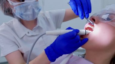 Patient woman on ultrasonic teeth cleaning procedure in dentistry, closeup view.