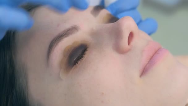 Levante el procedimiento de la pestaña de la laminación en clínica de belleza a la mujer joven, primer plano de la cara. — Vídeo de stock