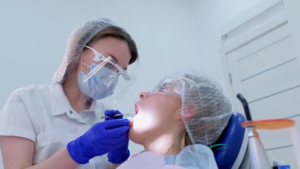 Οδοντίατρος βάζει βύσματα βαμβακιού στο στόμα των γυναικών στεγνά δόντια κατά τη διάρκεια υπερήχων καθαρισμού. — Αρχείο Βίντεο